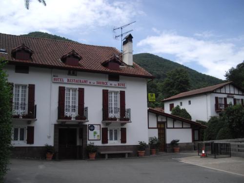 a white building with red shuttered windows at Les Sources de La Nive in Esterençuby