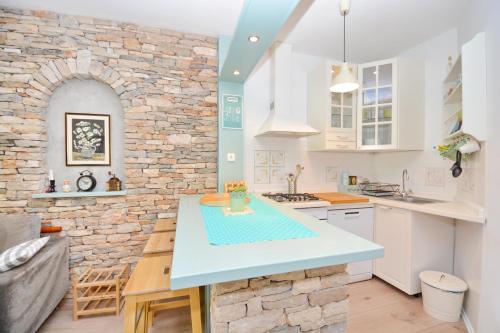 a kitchen with white cabinets and a stone wall at Bay House Rosohotnica in Vrboska
