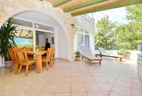 an outdoor patio with a wooden table and chairs at Bay House Rosohotnica in Vrboska