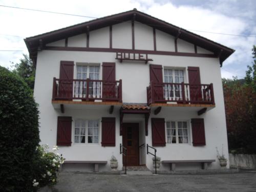 a white house with red shutters and balconies at Les Sources de La Nive in Esterençuby