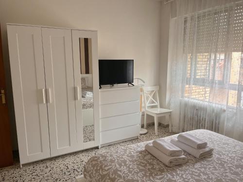 a white bedroom with a tv and a bed with towels at En Palencia capital céntrico con garaje Roberto in Palencia