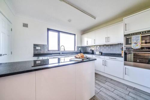 a large kitchen with white cabinets and black counter tops at Venn Down Lakes in Boscastle