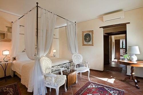 a bedroom with a canopy bed and two chairs at Torre Palombara - Dimora Storica in Narni
