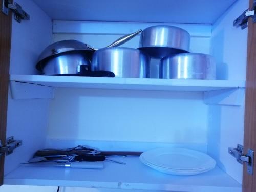 a shelf with pots and pans in a kitchen at Nash Issah Homes-1BedRoom in Nakuru
