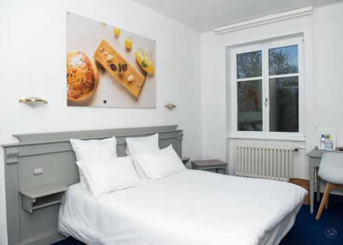 a bedroom with a white bed and a window at Hotel restaurant au gourmet in Drusenheim