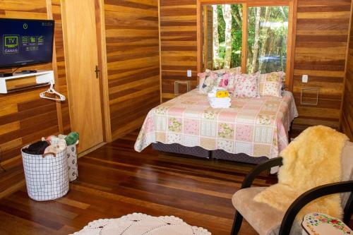 ein kleines Schlafzimmer mit einem Bett und einem TV in der Unterkunft Morada do Xaxim - Chalé Hortência in São Francisco de Paula