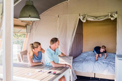 eine Gruppe von Personen, die in einem Zelt auf einem Bett sitzen in der Unterkunft Country Camp Campeggio Paradiso in Viareggio