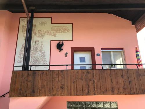 a pink house with a balcony with a cat on the wall at La tana alla Costa di Sessa in Sessa