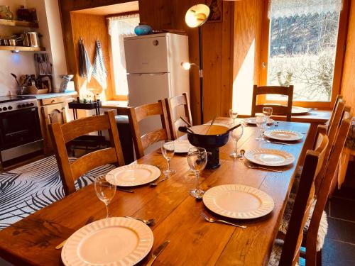 une table en bois avec des assiettes et des verres à vin dessus dans l'établissement Chalet Savoyard avec Cheminée et Parking à Samoëns - FR-1-624-80, à Samoëns