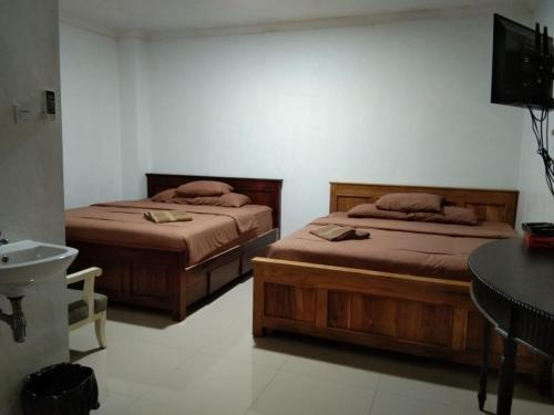 1 dormitorio con 2 camas, lavamanos y escritorio en Nexdeco House Homestay Syariah Solo, en Solo