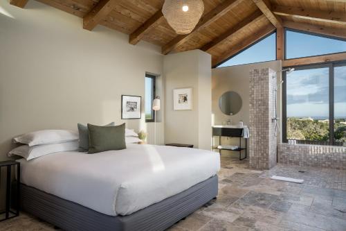 a bedroom with a white bed and a large window at Romansbaai Collection in Gansbaai