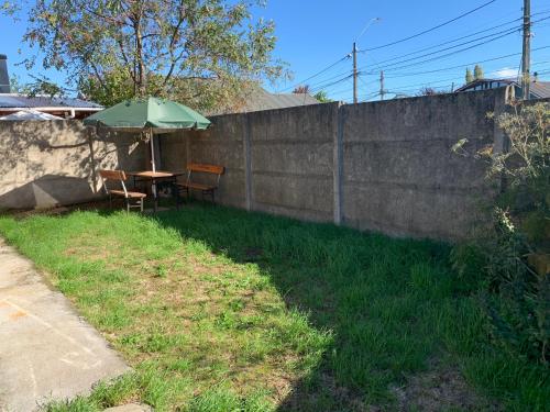 a table with an umbrella next to a wall at Casa de la Ribera Rengo in Valdivia