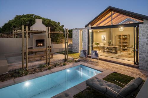 a house with a swimming pool and a fireplace at Romansbaai Collection in Gansbaai