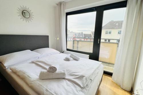 a white bed with two towels on it in front of a window at Bright Studio - Central - Balcony - Trade Fair in Düsseldorf