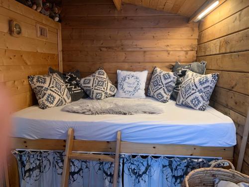 Una cama en una cabaña de madera con almohadas. en Bed & breakfast Duna met hammam, jacuzzi, sauna en Koksijde