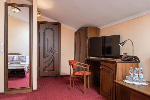 Habitación de hotel con TV y dormitorio en Edem Hotel Lviv, en Leópolis