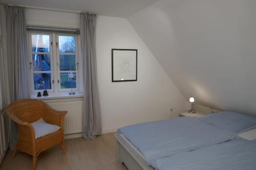 1 dormitorio con 1 cama, 1 silla y 1 ventana en Haus Sommerfrische, en Südstrand