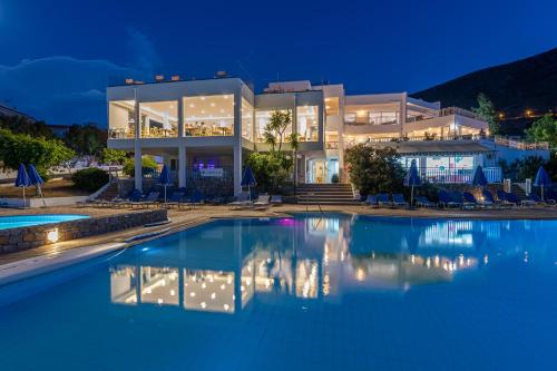 a villa with a swimming pool at night at Sunshine Village Hotel in Hersonissos