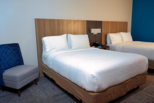 a hotel room with two beds and a chair at Holiday Inn Express Hotel & Suites Tampa-Oldsmar by IHG in Oldsmar