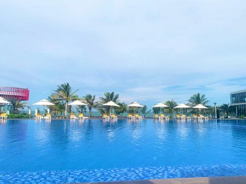 Oceanami Villa Long Hải - Vũng Tàu في لونغ هاي: مسبح كبير مع كراسي ومظلات