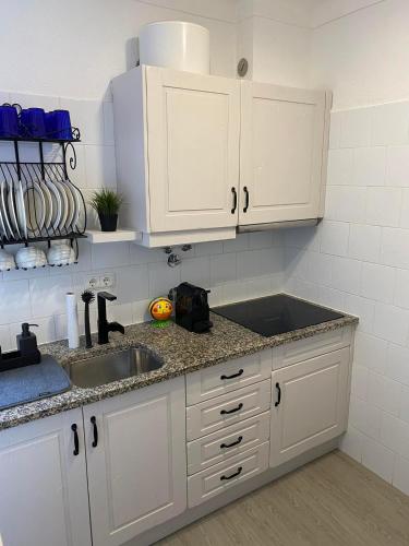 a kitchen with white cabinets and a sink at Vista Mar Aldeia de Marim in Marim
