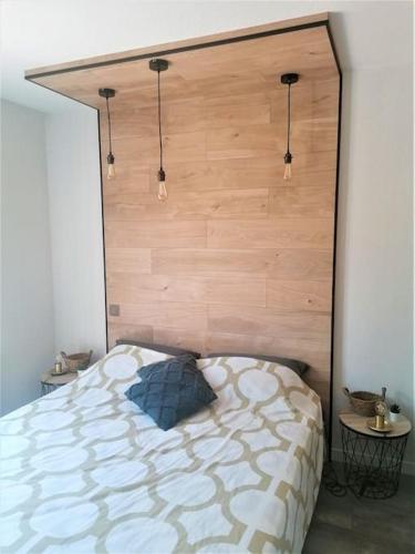 une chambre avec un lit avec une tête de lit en bois dans l'établissement Cosy Appart St Raph, piscine résidence, proche mer, à Saint-Raphaël