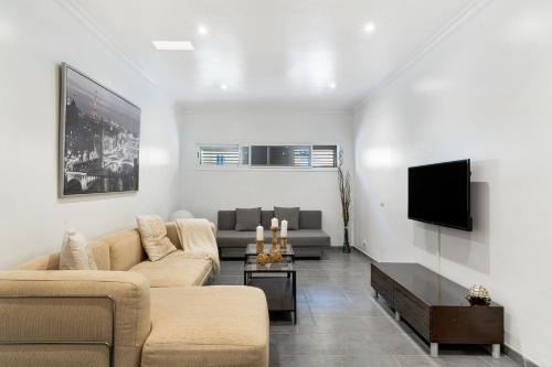 a living room with two couches and a flat screen tv at Moderno Triplex Sonneland in Maspalomas