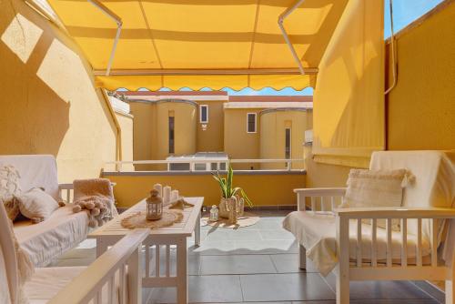 a balcony with chairs and a table and a yellow roof at Moderno Triplex Sonneland in Maspalomas