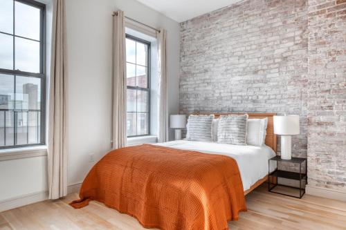 a bedroom with a brick wall and a bed with an orange blanket at East Village 2br w wd gym elevator nr cafes NYC-1044 in New York