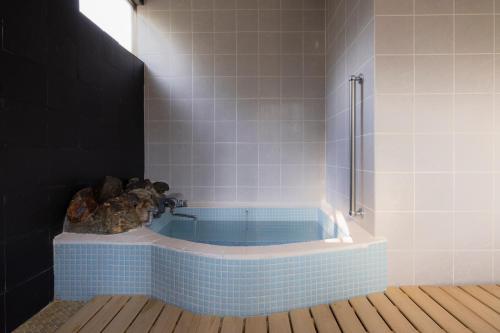 La salle de bains est pourvue d'une baignoire bleue et d'une douche. dans l'établissement Azumino Salon, à Azumino