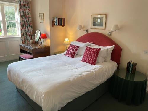 a bedroom with a large bed with a red headboard at Langrish House in Petersfield