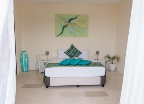 a white bedroom with a bed with blue pillows at Villa Atas Pelangi in Kuta Lombok