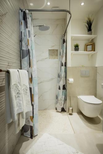 a bathroom with a toilet and a shower with towels at UUE TÄNAVA KORTER in Kuressaare