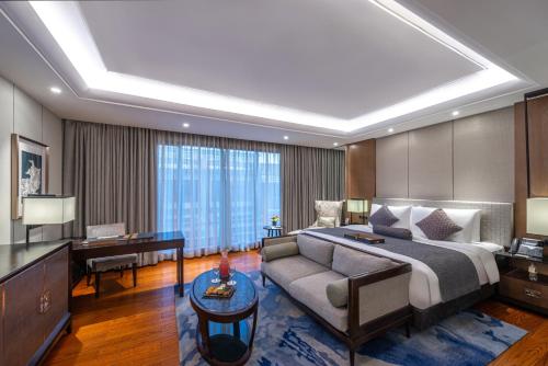 Narcissus Obhur Resort & Spa في جدة: غرفة في الفندق بها سرير وأريكة ومكتب
