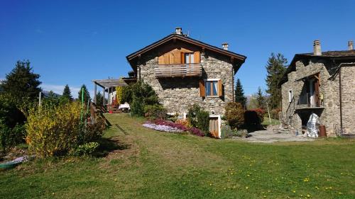 ein altes Steinhaus auf einem Grasfeld in der Unterkunft Casa delle Rose in Teglio