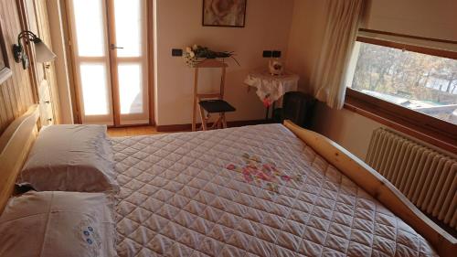 a large bed in a bedroom with a window at Casa delle Rose in Teglio