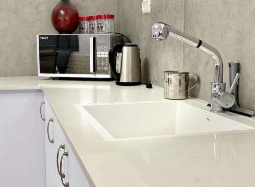 um balcão de cozinha branco com um micro-ondas e um lavatório em אחוזת רזים - Villa Razim em Safed