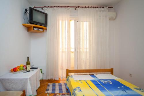 a bedroom with a bed and a tv and a table at Apartments Marko in Tivat