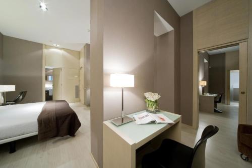 a bedroom with a bed and a desk with a lamp at Hotel Actual in Barcelona