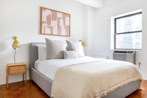 a white bedroom with a large bed and a window at Chelsea 1BR w Gym nr Penn Station MSG NYC-528 in New York