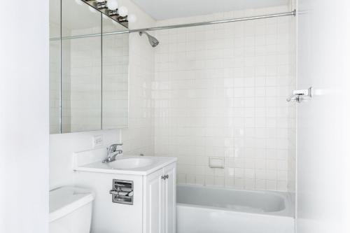 a white bathroom with a sink and a tub at Chelsea 1BR w Gym nr Penn Station MSG NYC-528 in New York