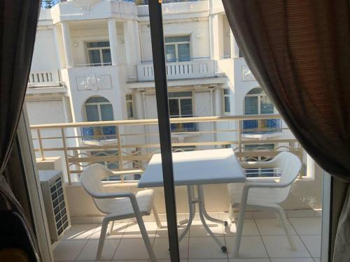 une table et des chaises blanches sur un balcon avec un bâtiment dans l'établissement Croisette immo Beau studio sur la Croisette, à Cannes