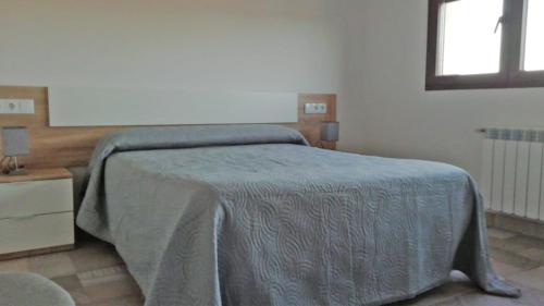 a bedroom with a bed with a blue blanket on it at Casa Rural Raiztruf in Cinctorres