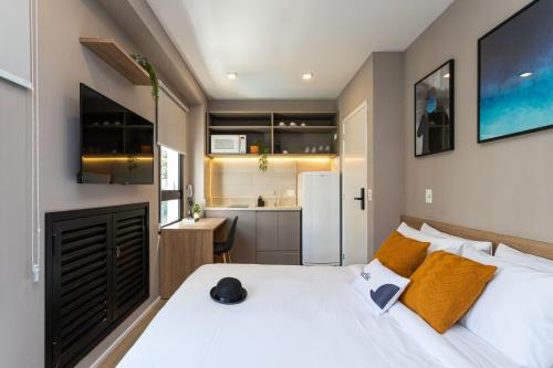 1 dormitorio con 1 cama blanca grande y cocina en Charlie Franca Jardim Paulista, en São Paulo
