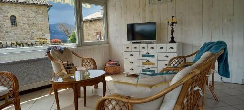 a living room with chairs and a tv and a table at Auberge Le Champêtre in Saint-Cierge-sous-le-Cheylard