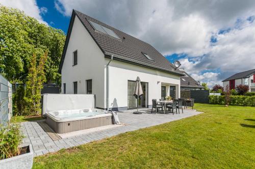 un patio trasero con bañera de hidromasaje y una casa en Luxus_Ferien_VILLA AMICI, en Göhren-Lebbin
