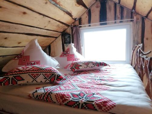 ein Schlafzimmer mit einem Bett mit Kissen und einem Fenster in der Unterkunft Casa rustica in Braşov