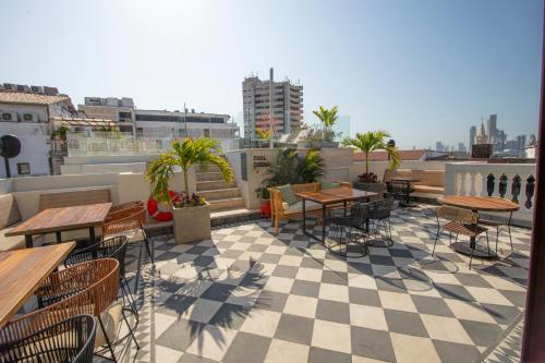 eine Terrasse mit Tischen und Stühlen auf dem Dach in der Unterkunft Voilá Centro Histórico in Cartagena de Indias