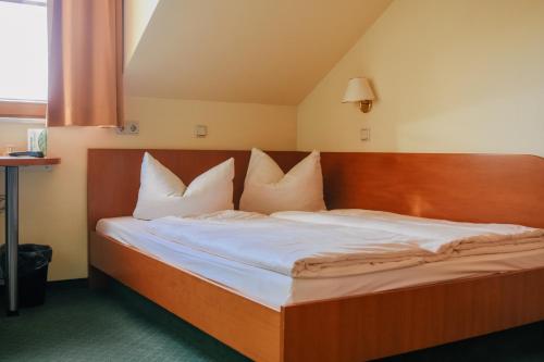 a bed with white pillows in a room at Landhotel Dresden in Dresden