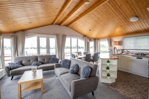 a living room with couches and a kitchen with windows at Tattershall Lakes Country Park in Tattershall